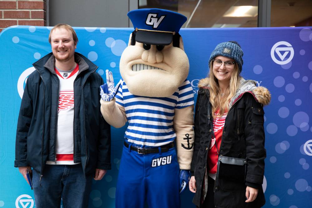 Two alumni pose with Louie at the Detroit Red Wings GVSU Night